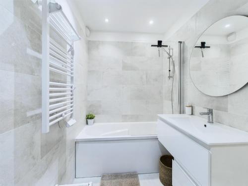 une salle de bain blanche avec un lavabo et un miroir dans l'établissement Appartement avec balcon vue mer, la Baule, à La Baule-les-Pins