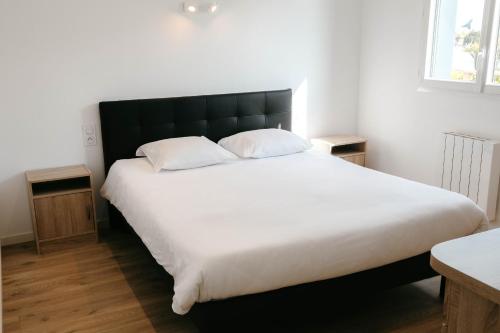 une chambre avec un grand lit blanc avec deux oreillers dans l'établissement 500m de la mer, maison moderne avec jardin pour 4, à Brignogan-Plage