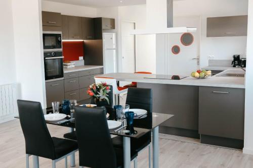 - une cuisine avec une table à manger, des chaises et un comptoir dans l'établissement 500m de la mer, maison moderne avec jardin pour 4, à Plounéour-Trez
