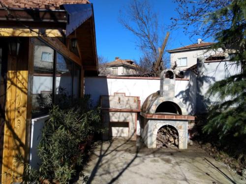 an outdoor pizza oven in a yard with a building at Харизма in Hisarya