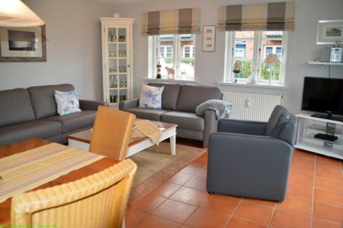 een woonkamer met een bank en een tv bij Wohnen auf'm Lande HT 6 in Oldsum