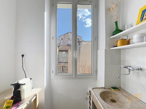 - une cuisine blanche avec une fenêtre et un évier dans l'établissement Appartement Central - Balcon & Lumineux - Les Frères de la Loc', à Marseille