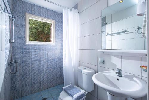 a white bathroom with a sink and a toilet at Primavera Beach Hotel Studios & Apartments in Malia