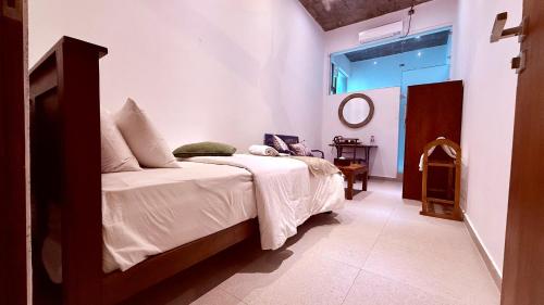 a bedroom with a bed with white sheets and a window at Coza Ceylon in Mount Lavinia