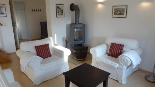 a living room with two white chairs and a stove at Galerie E MITTE in Gingst