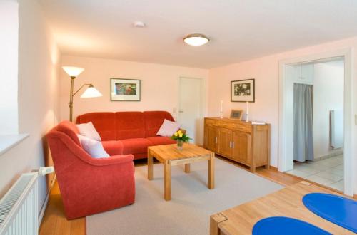 un salon avec un canapé rouge et une table dans l'établissement Haus Carmesin, à Eckernförde
