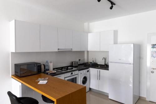 a kitchen with white appliances and a wooden table at Ground Garden View Apartments in Caesar Resort & SPA, Long Beach in Perivolia tou Trikomou