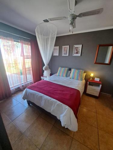 a bedroom with a large bed with a red blanket at Addo's Secret Backdoor in Gqeberha