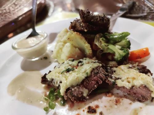 a plate of food with meat and vegetables and sauce at Dom Pedros Haven Resort - Tranquil Retreat by the Sea in Utorda