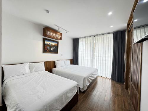 a hotel room with two beds and a window at CHAMECO ART Boutique Home Danang in Da Nang