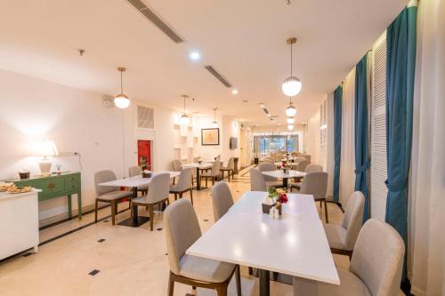 a restaurant with white tables and chairs and a counter at Minasi HanoiOi Lakeside Hotel in Hanoi