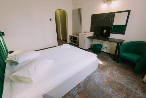 a hotel room with a white bed and a chair at Hotel Victoria in Cluj-Napoca