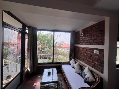 a living room with a couch and a brick wall at Avocado Accommodations in Khadkagaon