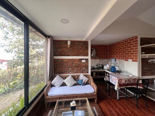 a living room with a couch and a brick wall at Avocado Accommodations in Khadkagaon