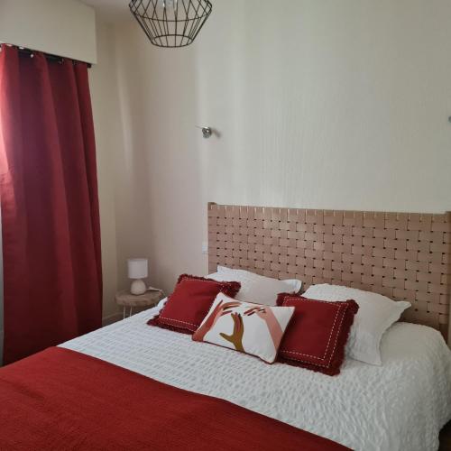 une chambre avec un lit avec des oreillers rouges et blancs dans l'établissement Appartement Escale Roz Pleine vue sur le Port, à Perros-Guirec