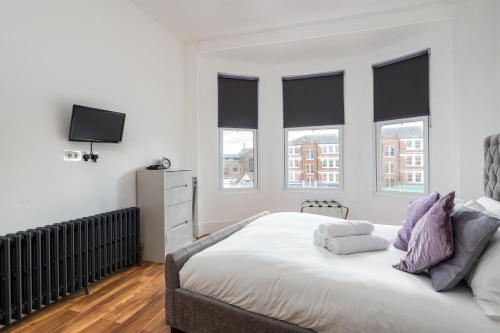 a bedroom with a large white bed with windows at Stunningly Luxurious London Apartment (MHB350) in London