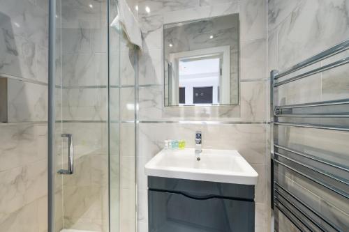 a bathroom with a sink and a shower and a mirror at Stunningly Luxurious London Apartment (MHB350) in London