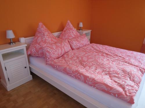 a bed with pink and white sheets and pillows at Ferienwohnung am Gässle in Ettenheim