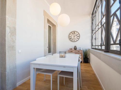 a white table and chairs in a room with a clock at Rent Top Apartments Rambla Catalunya in Barcelona