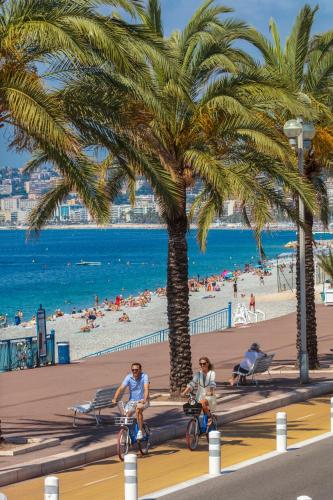 2 personnes à vélo sur la plage sous un palmier dans l'établissement Le Campus Appartement, à Nice