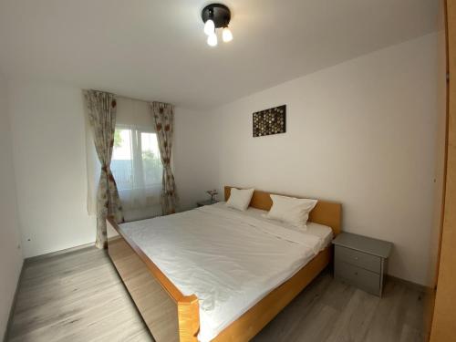 a bedroom with a bed with white sheets and a window at Central Apartment in Blaj