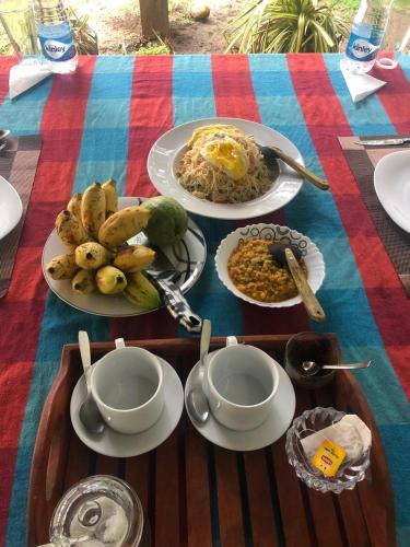 a table with plates of food on a colorful table cloth at lake paradise cabana in Tissamaharama