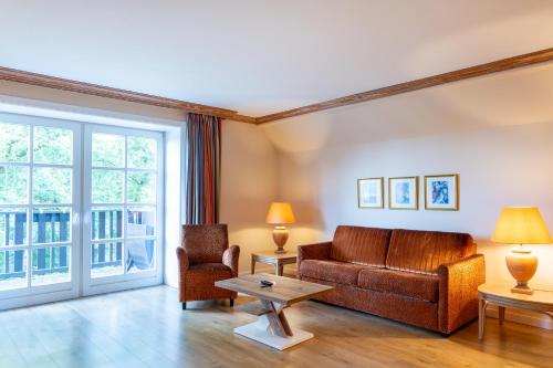 a living room with a couch and a chair at Hotel Landhaus Höpen in Schneverdingen