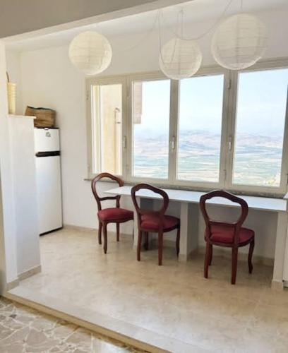 a kitchen with four chairs and a table with windows at Mineo Townhouse with incredible views of Mt Etna in Mineo