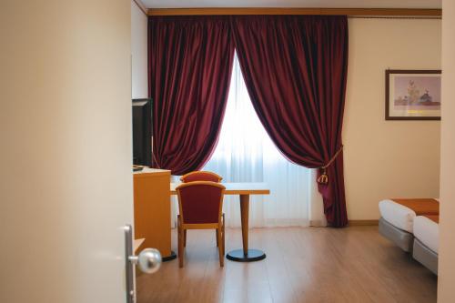 a room with a desk and a bed and a red curtain at Best Western Mirage Hotel Fiera in Paderno Dugnano