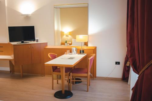 a room with a desk and a table and a tv at Best Western Mirage Hotel Fiera in Paderno Dugnano