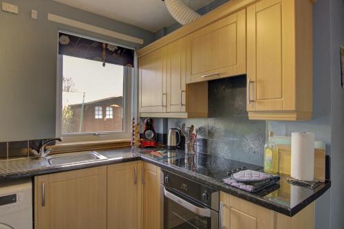 a kitchen with wooden cabinets and a sink at Kavija, Invergordon in Invergordon