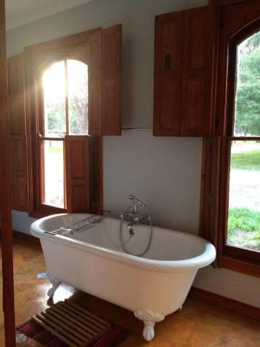a large white tub in a room with two windows at Murrayfield Karoo Guest Villa in Nieu-Bethesda
