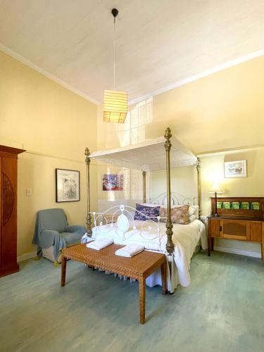 a bedroom with a canopy bed and a table at Murrayfield Karoo Guest Villa in Nieu-Bethesda