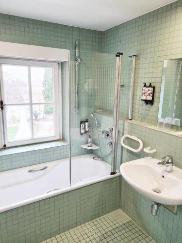 a green tiled bathroom with a tub and a sink at Hôtel Château Schengen in Schengen