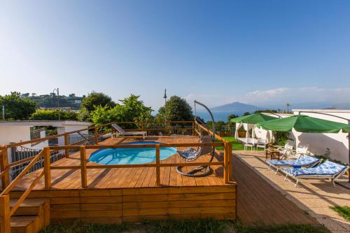 a large deck with a pool and chairs and umbrellas at Appartamento in Villa con Terrazzo e Vista Golfo in Massa Lubrense