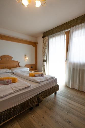 a bedroom with two beds and a large window at Wellness Hotel Lupo Bianco in Canazei