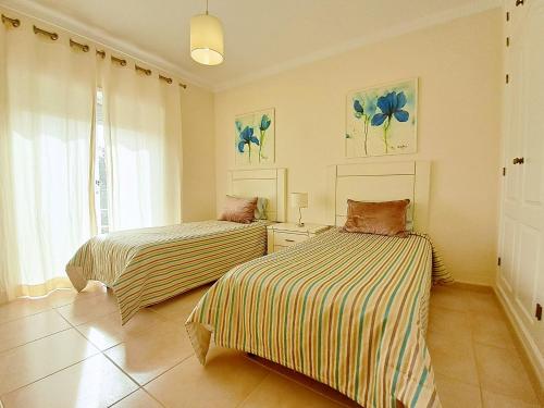 two beds in a room with a window at Apartamento Oásis Parque 1 in Portimão