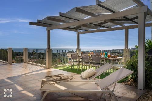 eine Terrasse mit einer Pergola, einem Tisch und Stühlen in der Unterkunft Villa Begonia by Abahana Villas in Fanadix