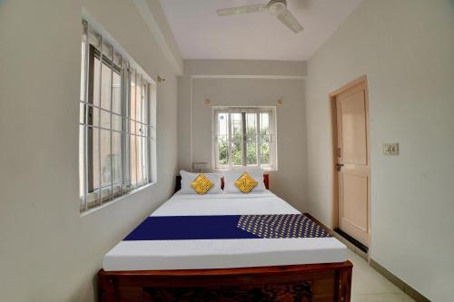 a bed in a room with two windows at Hotel O Fortuner Palace in Bengaluru