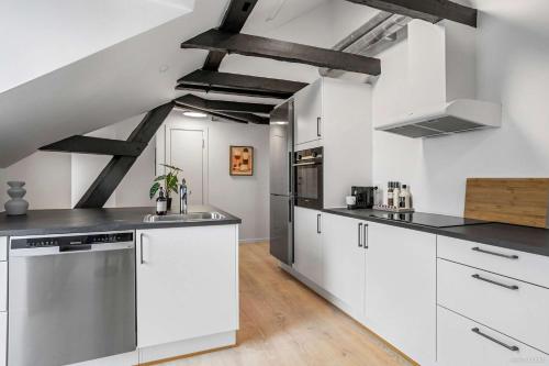 a kitchen with white cabinets and black counter tops at City-Center Penthouse w Private Balcony in Aarhus