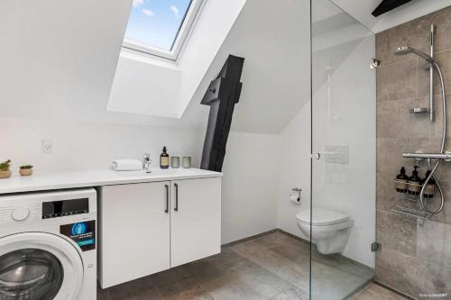 a bathroom with a washing machine and a toilet at City-Center Penthouse w Private Balcony in Aarhus