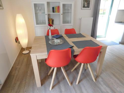 a dining room table with four red chairs around it at Pfarrscheune in Bad Sülze