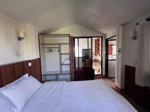 a bedroom with a white bed and a large mirror at Avocado Accommodations in Khadkagaon