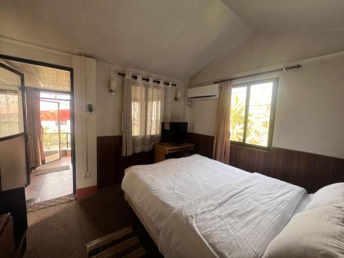 a bedroom with a bed and a tv and two windows at Avocado Accommodations in Khadkagaon
