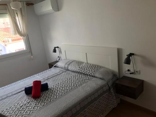 a bedroom with a bed with a red hat on it at Pis Sitges centre in Sitges