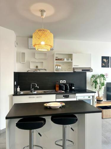 - une cuisine avec un évier et deux tabourets de bar dans l'établissement Ô Palomaya, à Montpellier