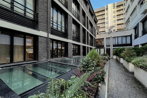 - une vue extérieure sur un bâtiment avec une piscine dans l'établissement PARISIAN HOME l MARAIS, à Paris