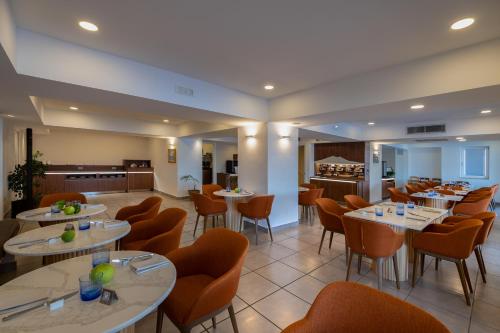 a restaurant with white tables and orange chairs at Relais Manfredi in Castellammare di Stabia