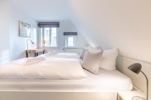 a white bed with white sheets and pillows at Reethus WE 4, Seeschwalbe in Borgsum