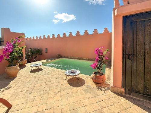 a swimming pool in a courtyard with potted plants at RIAD PRIVATIF avec Piscine Chauffée au Cœur de la Médina et Petits-Déjeuners Inclus in Marrakech